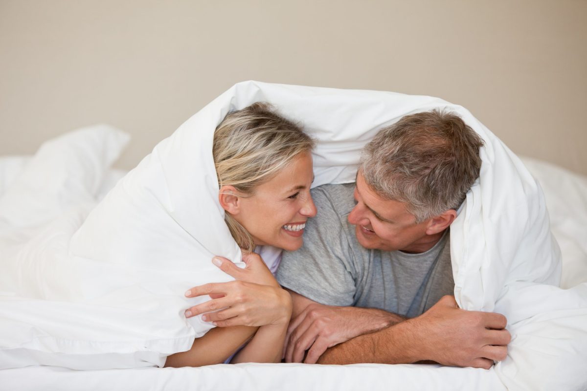 Couple lying down in their bed at home